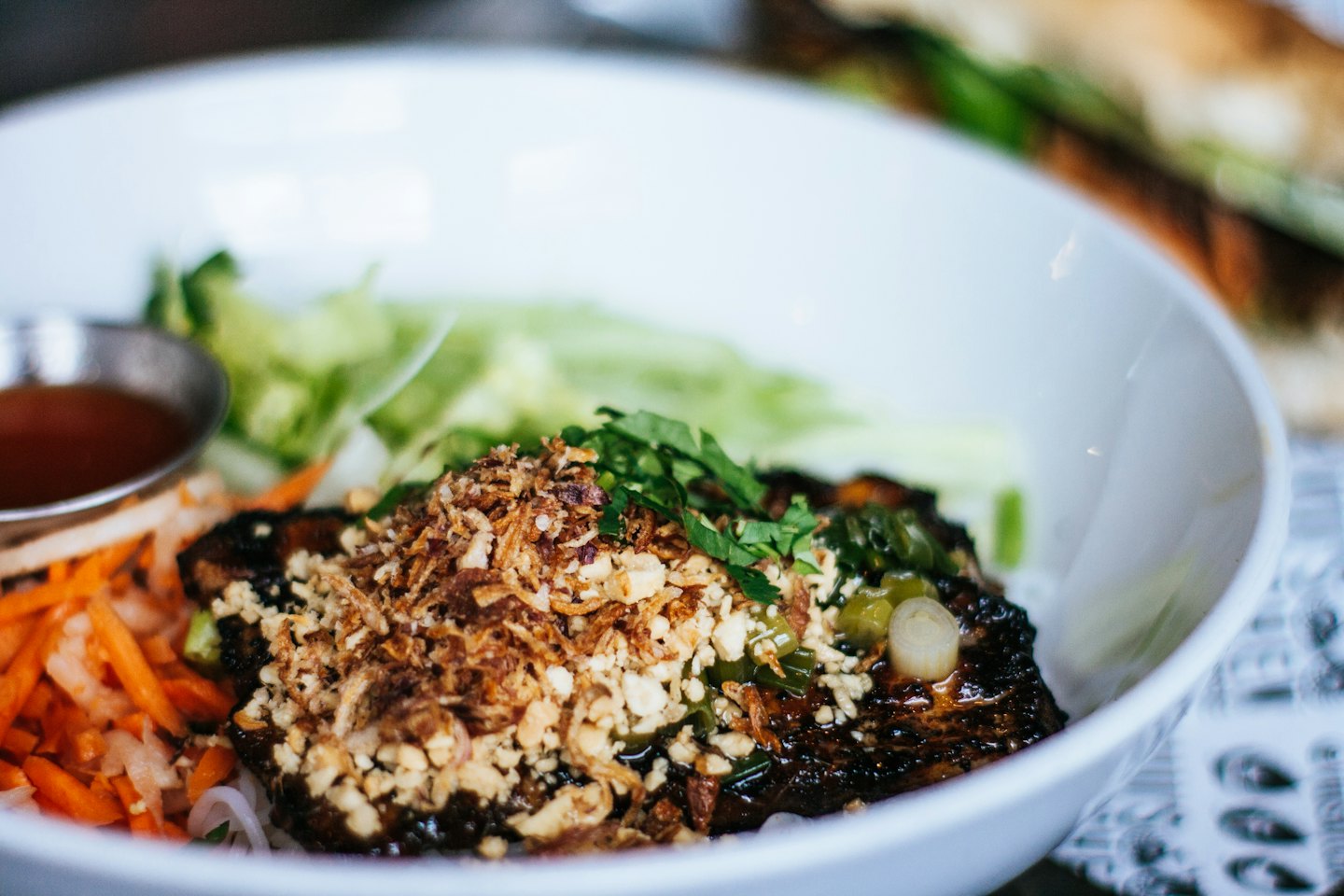Bowl of noodle salad topped with grilled meat and herbs.